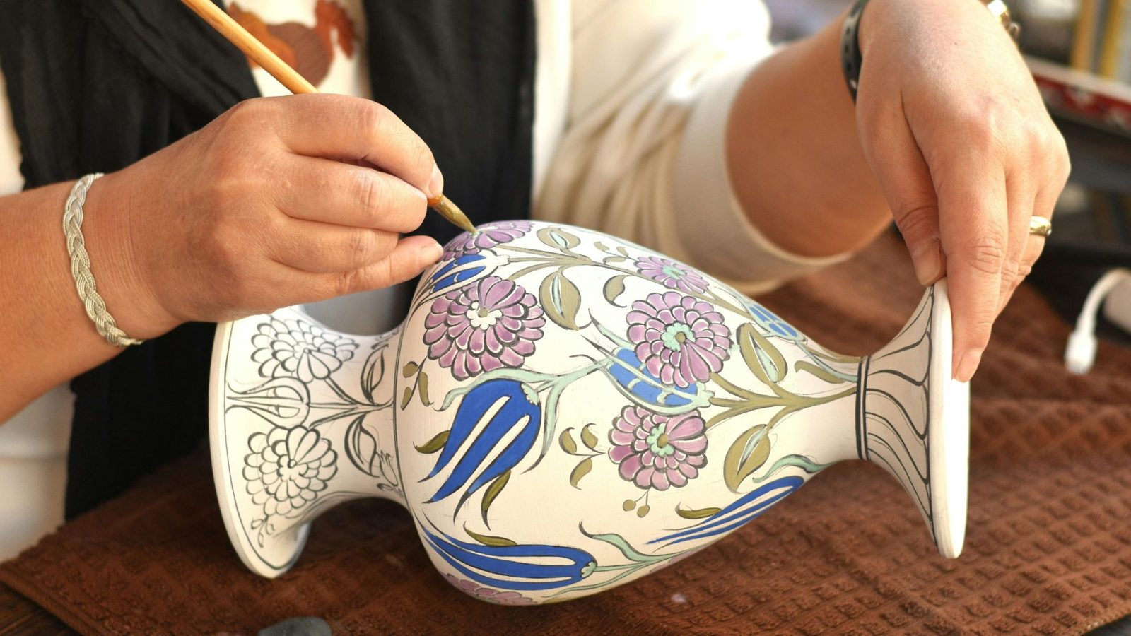 Artesã pintando um vaso de cerâmica